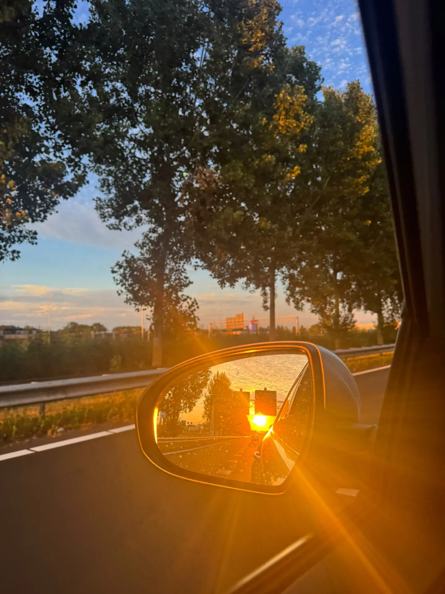 Golden sunset reflected in the wing mirror during a journey