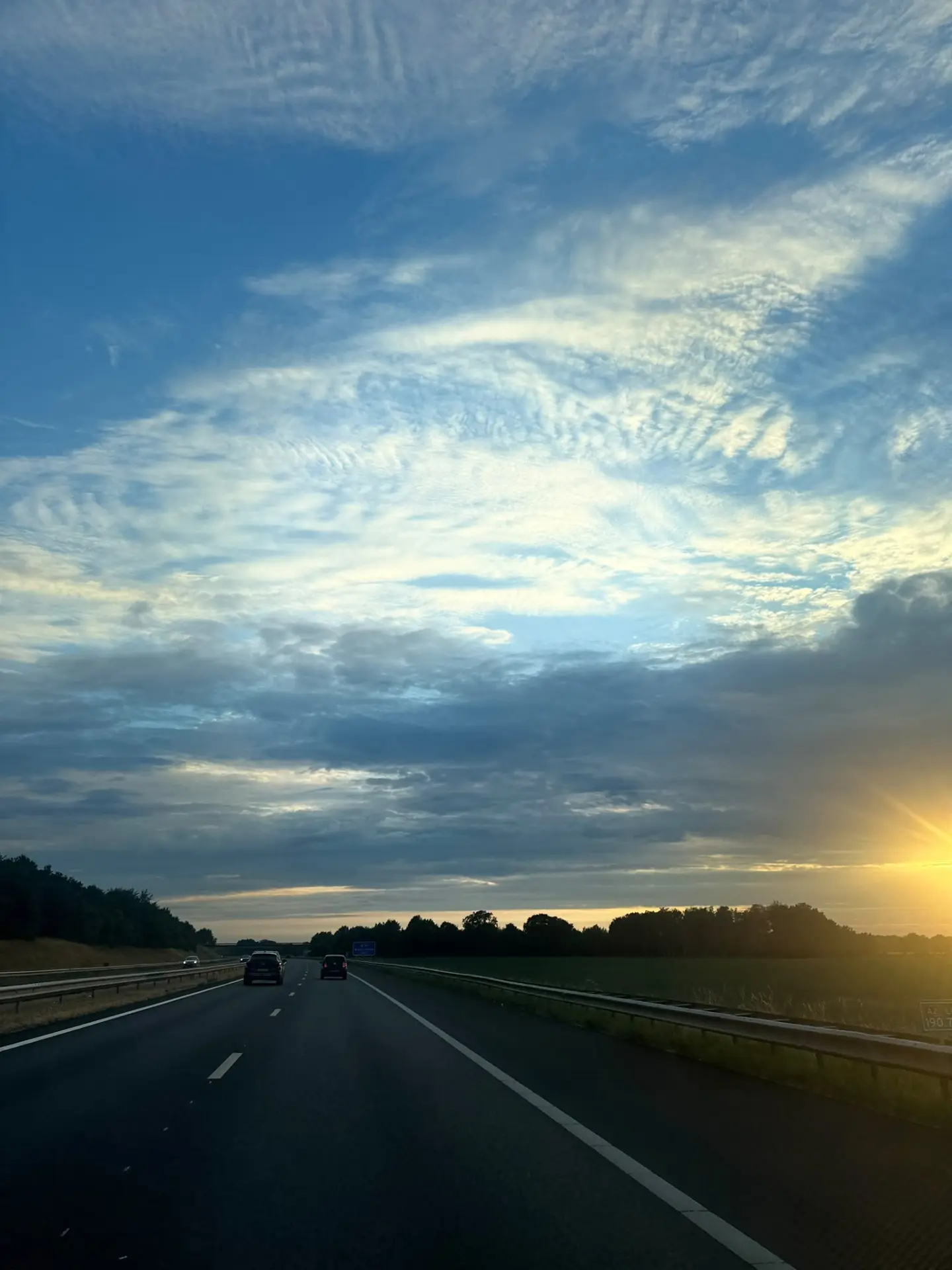 Open motorway at sunrise under a wide cloudy sky